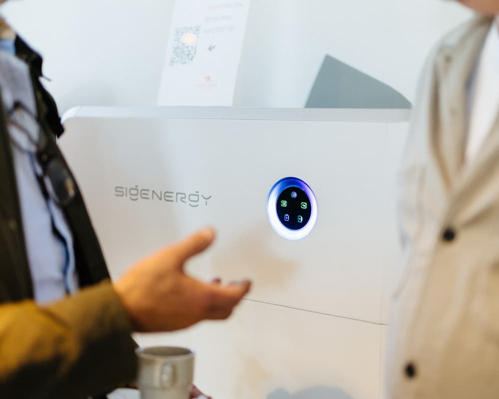 Två personer samtalar framför ett hembatteri för solceller